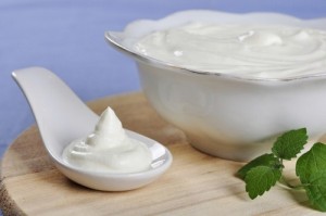Sour cream in spoon on wooden cutting board. Small shallow DOF.